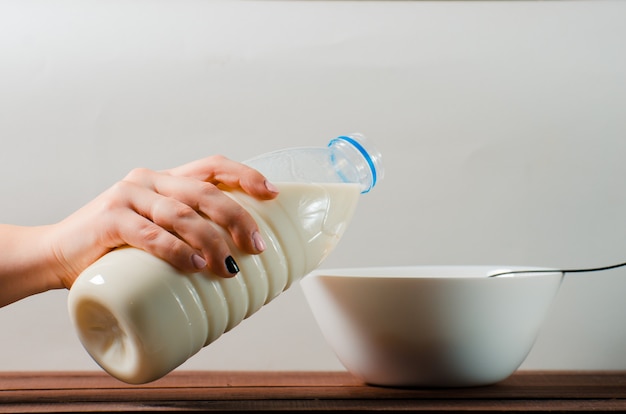 Une bouteille de lait dans une main féminine sur une plaque blanche. EA sain