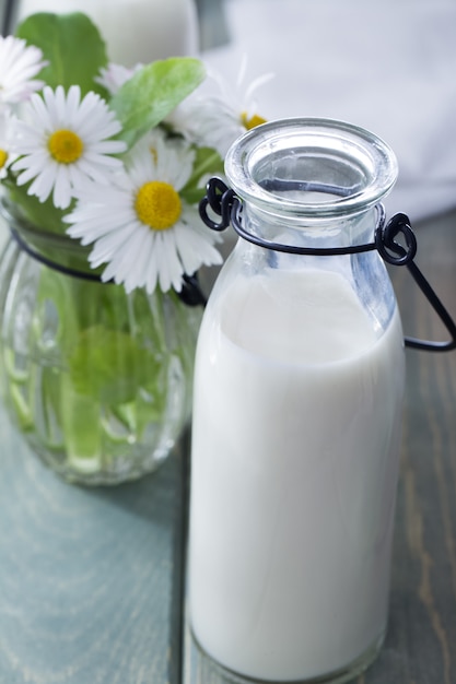 Photo bouteille de lait et de fleurs d'été sur fond de bois