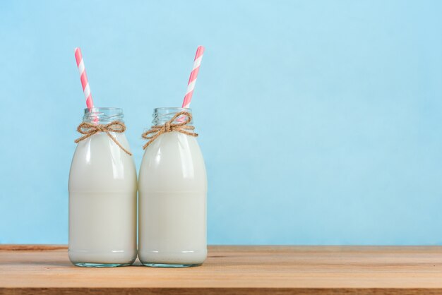 Une bouteille de lait avec de la paille sur une table en bois