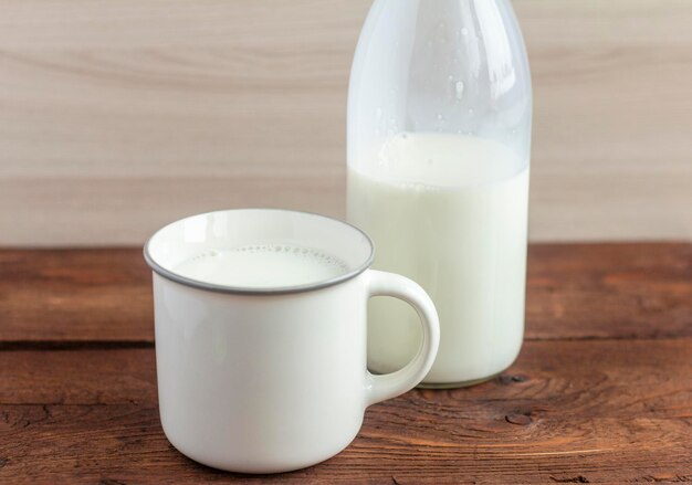 Une bouteille de lait et une tasse de lait sur une table en bois.