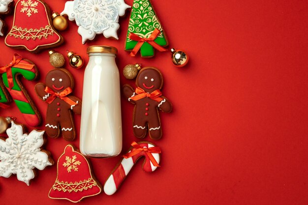 Bouteille de lait en verre et biscuits de pain d'épice de Noël sur fond rouge