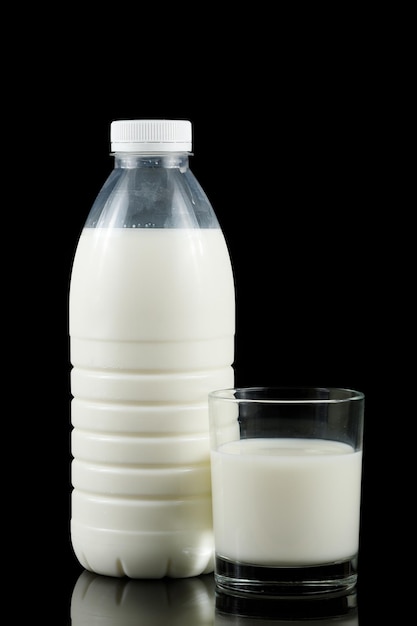 Une bouteille de lait et un verre sur fond noir