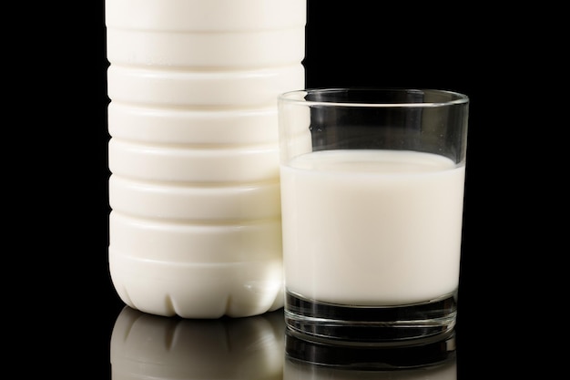 Une bouteille de lait et un verre sur fond noir