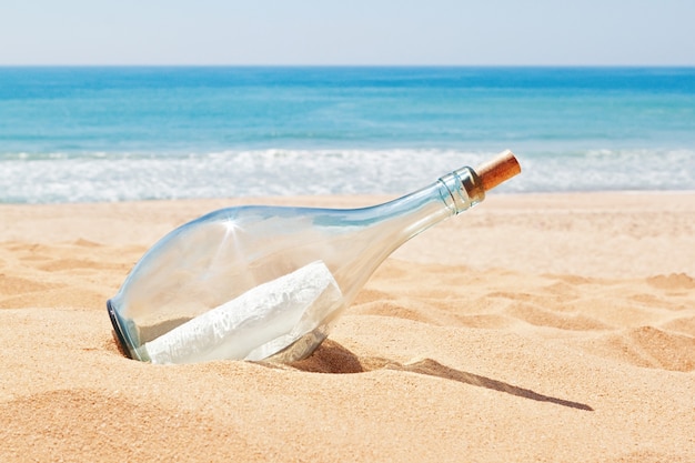 Une bouteille avec une lettre de détresse sur la plage. Été.