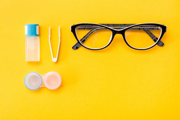 une bouteille de liquide, un récipient et des pincettes, des lunettes sur un fond jaune