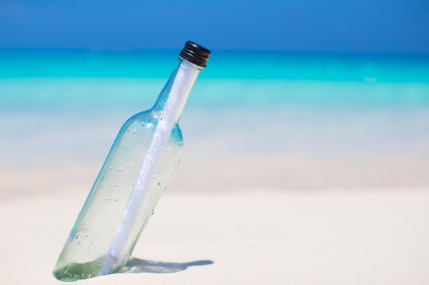 Bouteille avec un message enfoui dans le sable blanc