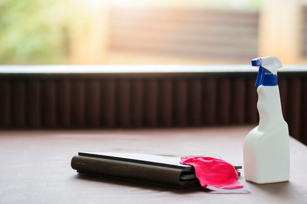 Une bouteille de nettoyant et un masque médical sur une table de restaurant