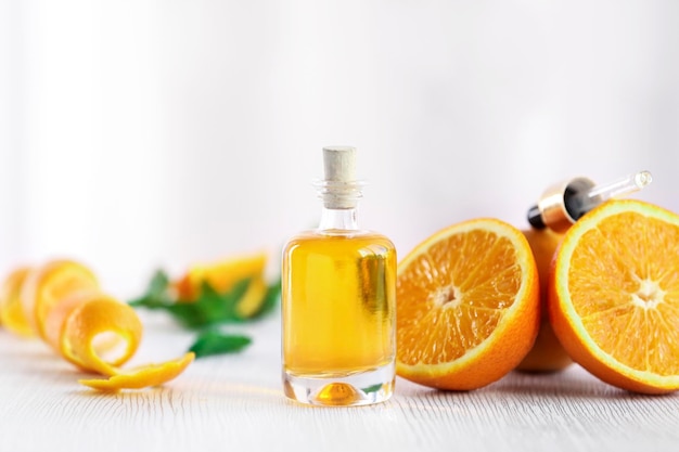 Bouteille avec des oranges à l'huile essentielle et peler sur une table en bois