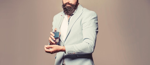 Bouteille de parfum ou d'eau de Cologne et parfumerie, cosmétiques, bouteille d'eau de Cologne parfumée, homme tenant de l'eau de Cologne. Parfum masculin, homme barbu en costume. Homme tenant une bouteille de parfum. Parfum homme, parfum