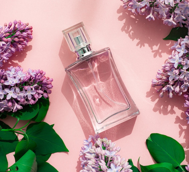 Une bouteille de parfum et de lilas sur fond rose