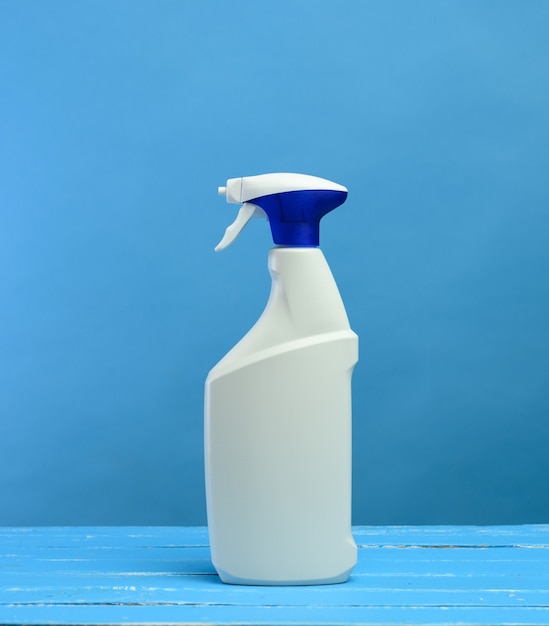 Bouteille en plastique blanc avec vaporisateur et buse en mousse avec détergent sur mur bleu