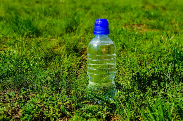 Bouteille en plastique avec de l'eau claire dans l'herbe verte