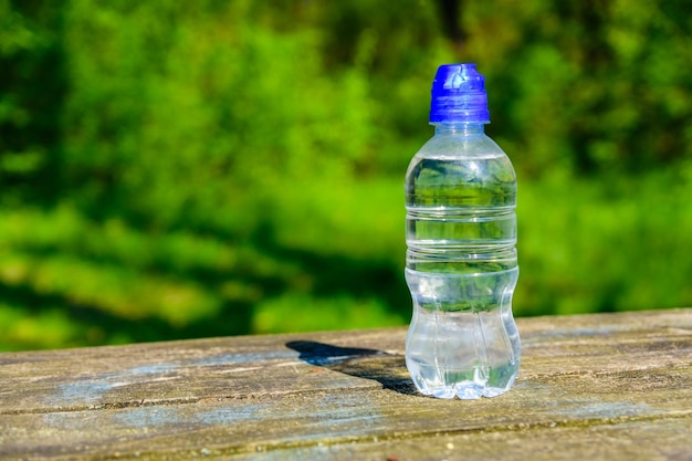 Bouteille en plastique avec de l'eau claire sur une table en bois rustique