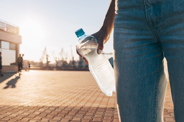 Bouteille en plastique avec de l'eau froide dans une main féminine