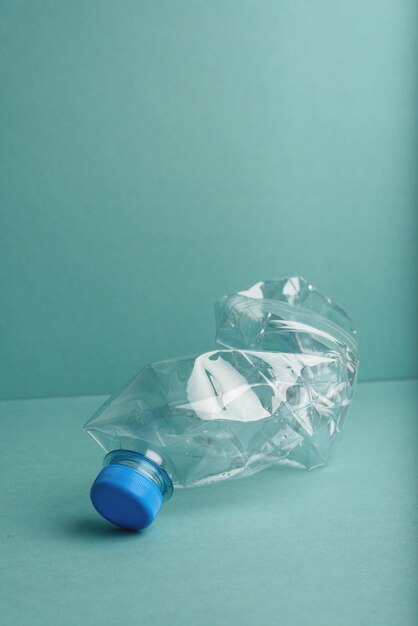 Bouteille en plastique écrasée utilisée sur le fond bleu