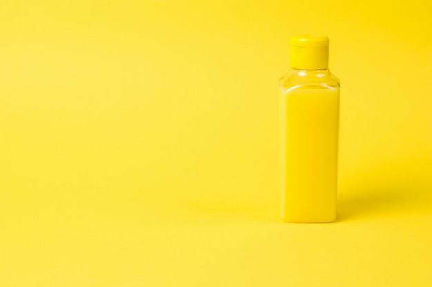 Bouteille en plastique avec liquide jaune sur fond jaune