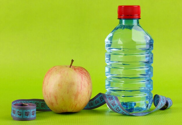 Bouteille de pomme d'eau et ruban à mesurer sur fond vert