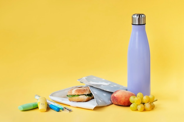 Bouteille réutilisable et emballage à sandwich sur fond jaune vif Concept de durabilité