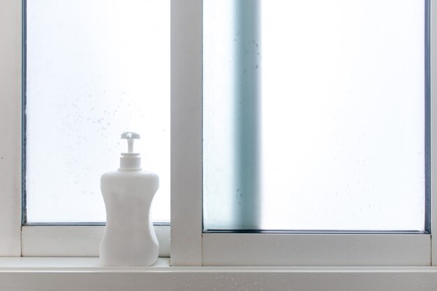 Une bouteille de savon ou de shampoing au bord des fenêtres de la salle de bain.