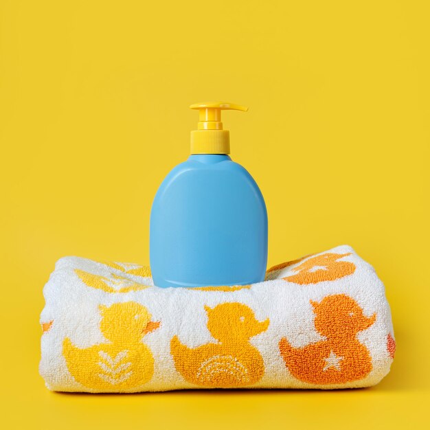 Bouteille de savon ou de shampoing et serviette pour bébé avec de jolis canards sur fond jaune. Accessoires de bain