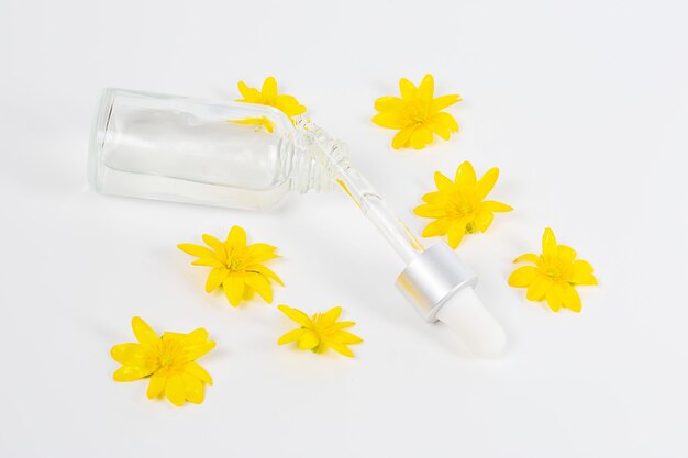 Une Bouteille Avec Un Sérum De Pipette Sur Un Fond Blanc Entouré De Fleurs Printanières Jaunes