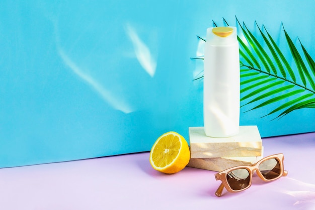 Une bouteille de shampoing, des lunettes de soleil et un citron