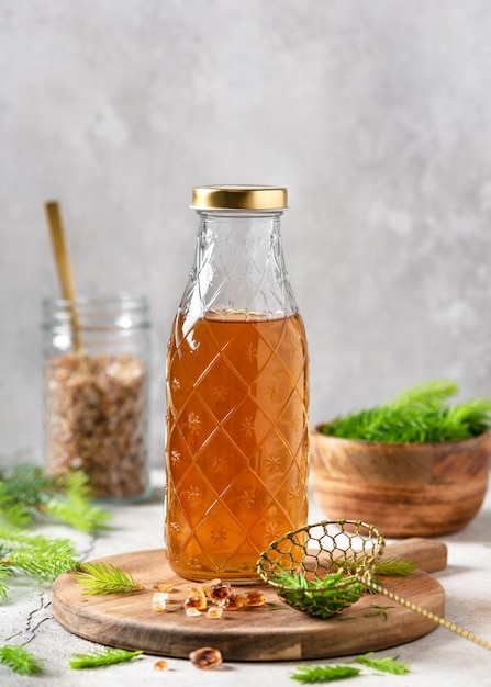 bouteille de sirop fait maison à base de jeunes pointes d'épinette et de sucre naturel sur la planche à découper en bois