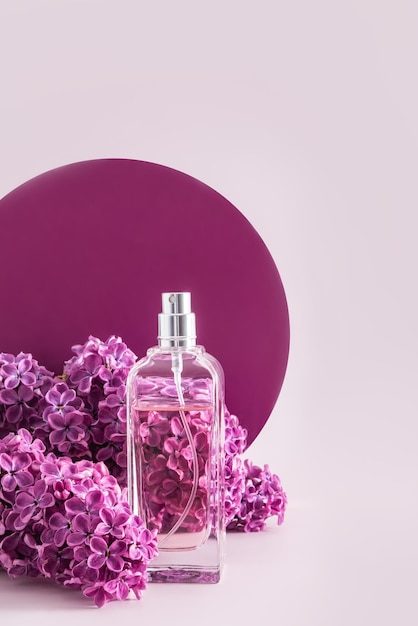 Une bouteille de spray cosmétique ou de parfum sur un fond de fleurs de lilas délicates et d'une passerelle ronde Vue verticale Présentation du produit