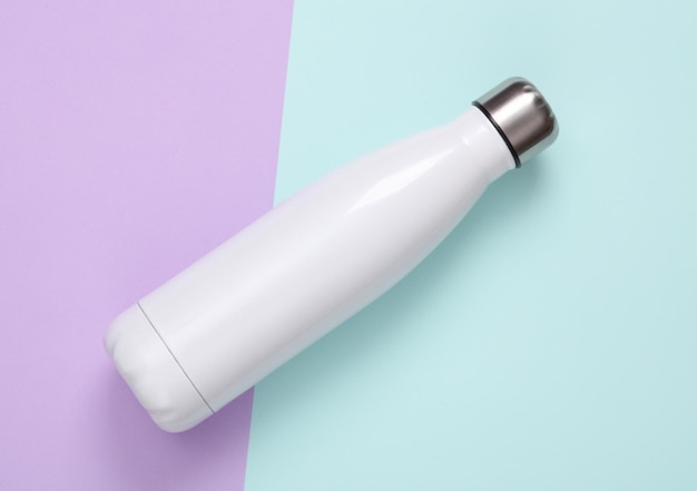 Bouteille thermique métallique blanche pour l'eau sur un fond pastel Bouteille thermale isolée en acier inoxydable sous vide