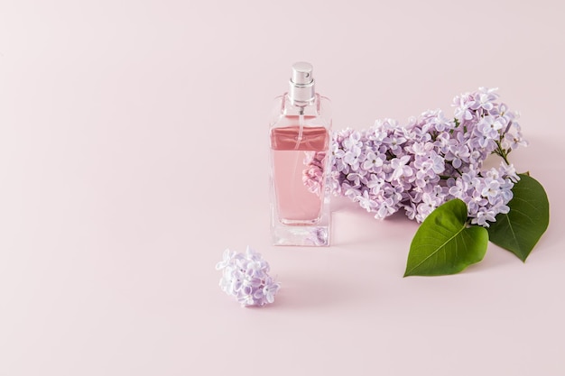 Une bouteille transparente de parfum ou d'eau de bowling de toilette sur fond violet avec branche lilas une copie de l'espace