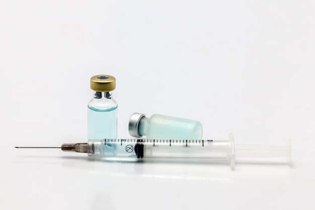 Photo bouteille de vaccin isolée en verre et en plastique une allongée avec un liquide coloré et une seringue