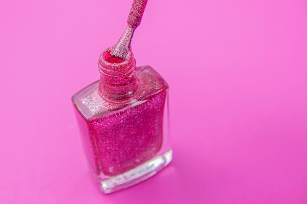 Bouteille de vernis à ongles rose givré avec pinceau sur fond rose