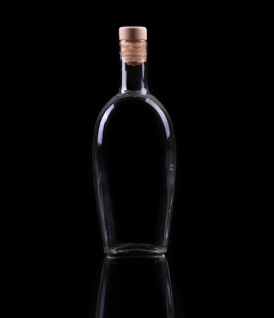 Bouteille et verre d'alcool isolé sur fond noir.