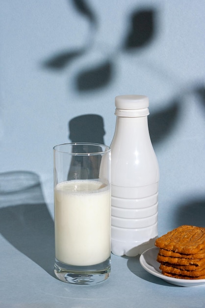 Bouteille en verre avec des biscuits au yogourt sur fond bleu à l'ombre d'un arbre petit-déjeuner matinal