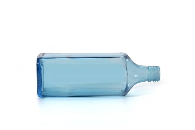 Bouteille en verre bleu de dry gin allongé sur fond blanc