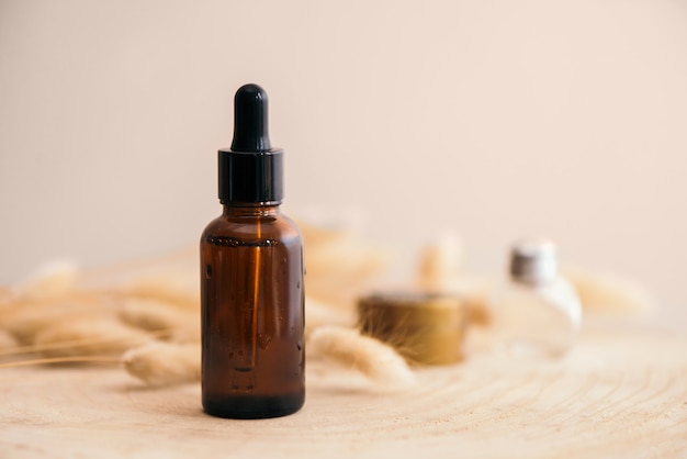 Bouteille en verre de couleur brune avec du sérum de vitamine sur un support en bois