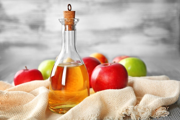 Bouteille en verre avec du vinaigre de pomme et des fruits frais sur la table