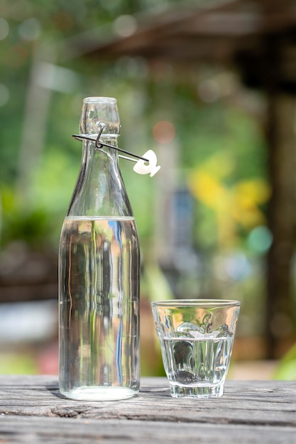 Photo bouteille et verre avec de l'eau sur la table en bois