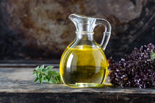 Bouteille en verre avec de l'huile d'origan sur une surface en bois