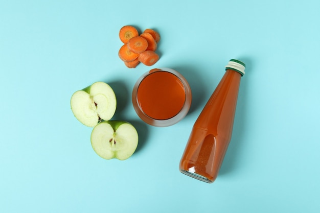 Bouteille et verre de jus et ingrédients sur fond bleu isolé