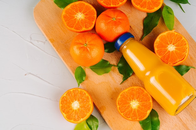 Bouteille en verre de jus d'orange avec des moitiés d'oranges mûres