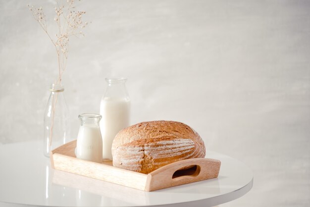 Bouteille en verre de lait avec du pain sur un plateau en bois isolé sur fond blanc pour la nourriture et le concept sain. avec espace de copie pour le texte