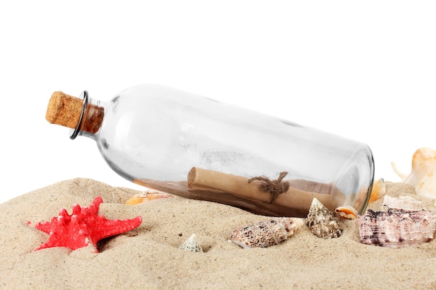 Photo bouteille en verre avec note à l'intérieur sur le sable isolé sur blanc