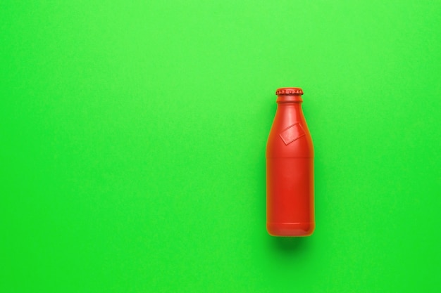 Une bouteille en verre rouge fermée sur un fond vert clair. Le concept de boissons rafraîchissantes.