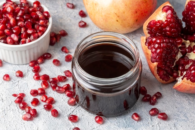 Bouteille en verre de sauce aigre à la grenade avec des fruits de grenade frais entiers et fendus (nom turc; nar eksisi)