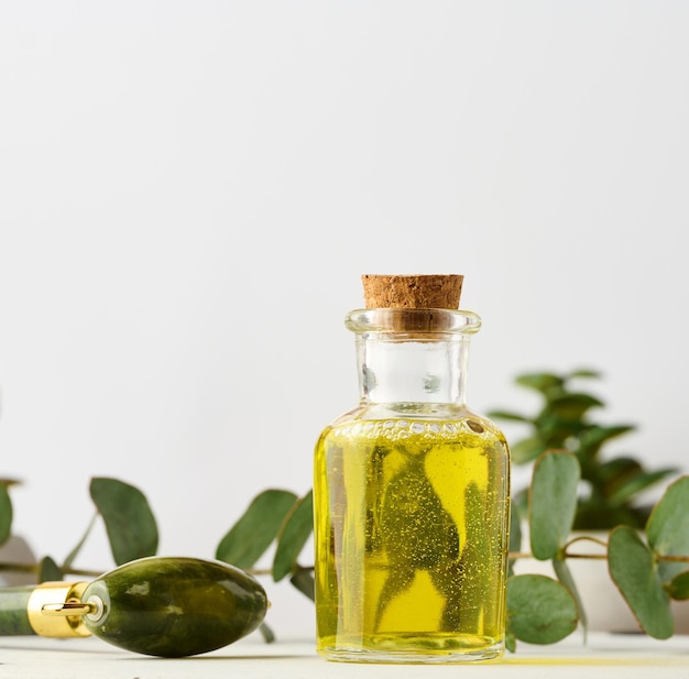 Bouteille en verre transparent avec produit cosmétique de branche d'huile jaune et d'eucalyptus