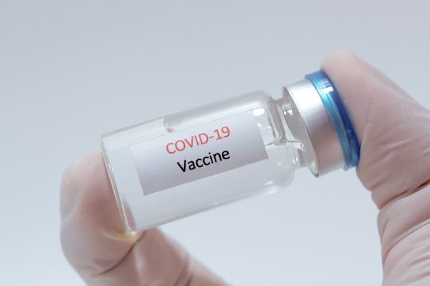 Bouteille en verre de vaccin COVID-19 (Coronavirus) dans la main d'un médecin