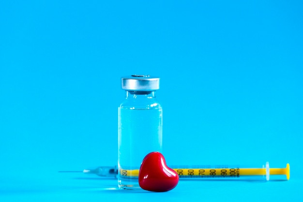 La bouteille en verre de vaccination avec une seringue et un petit coeur rouge