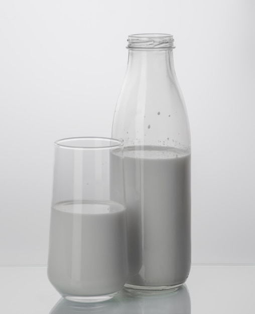 Bouteille en verre et verre de lait sur fond blanc