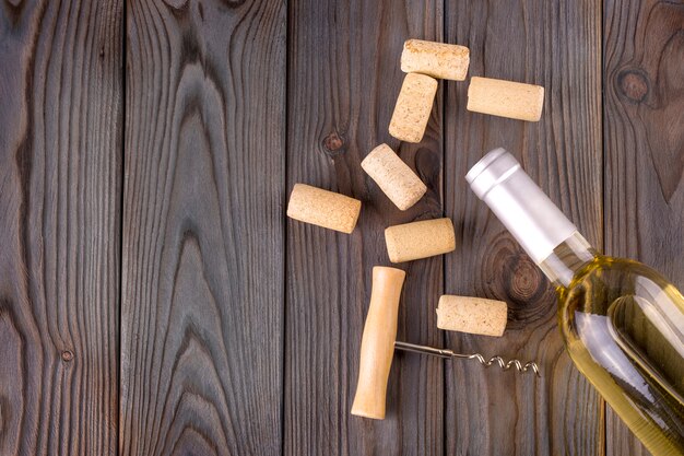 Bouteille en verre de vin avec des bouchons en liège sur fond de table en bois.